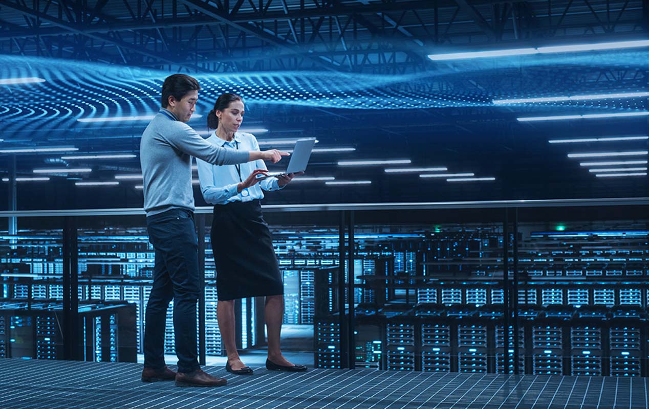 Two Bell professionals collaborate on a laptop in digital environment, symbolizing Bell’s sustainable ecosystem powering Canada's AI future.